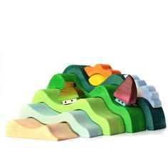 a wooden toy with mountains and houses on it's sides, in front of a white background