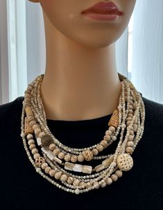 One-of-a-kind multi-strand statement necklace handcrafted in Scottsdale, Arizona. Beads: 10 strands of shell, MOP, carved bone and brass. Dimensions: approximately 21" + 2.5" extender. ﻿Make a Statement ﻿﻿with this necklace featuring a unique mix of natural materials! Note: the necklace on the bust has been paired with a pendant from the Inspired by Art Collection. They are sold separately. See the pendant here﻿. ﻿Free Shipping Refund Policy Bohemian Multi-strand Beige Jewelry, Beige Bohemian Multi-strand Jewelry, Bohemian Beige Multi-strand Jewelry, Multi-strand Mother Of Pearl Beaded Necklaces, Vintage Multi-strand Wooden Beads Jewelry, Unique Multi-strand Wooden Beaded Necklaces, Multi-strand Beaded Mother Of Pearl Necklace, Multi-strand Mother Of Pearl Beaded Necklace, Handmade Beige Multi-strand Jewelry