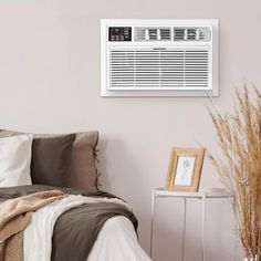 an air conditioner mounted on the wall above a bed