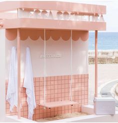 a pink and white building with towels hanging from it's roof next to the ocean