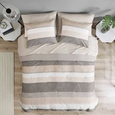 an overhead view of a bed with two pillows and one pillow on the floor next to a lamp