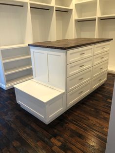 an empty room with white cabinets and drawers on the floor in front of shelves that are open