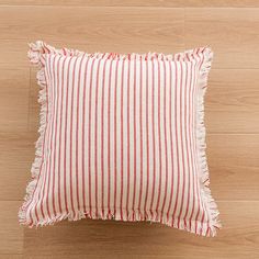 a red and white striped pillow sitting on top of a wooden floor