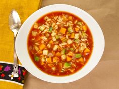 a white bowl filled with soup on top of a yellow towel next to a spoon