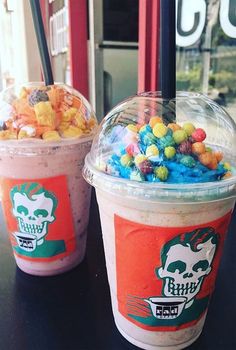 two cups filled with cereal and candy on top of a table next to each other