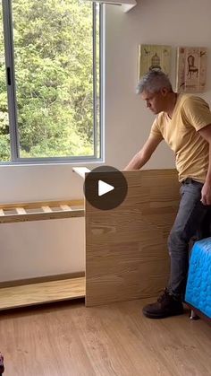 a man standing on top of a bed next to a blue mattress in a bedroom