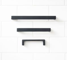 two black shelfs on a white tiled wall