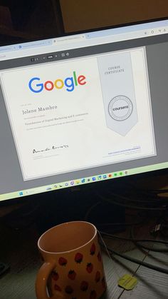 a computer monitor sitting on top of a desk next to a coffee cup and keyboard