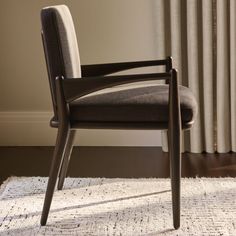 a chair sitting on top of a white rug next to a window covered in curtains