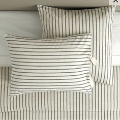 two striped pillows sitting on top of a bed