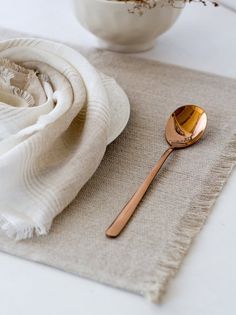 a wooden spoon sitting on top of a table next to a white bowl filled with flowers