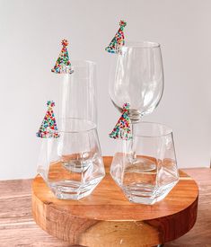 three wine glasses sitting on top of a wooden table next to each other with colorful decorations