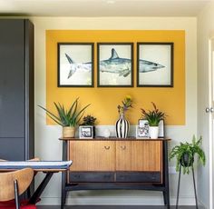 a living room with yellow walls and pictures on the wall