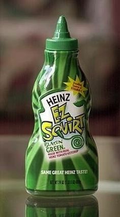 a close up of a bottle of green liquid on a table with a blurry background