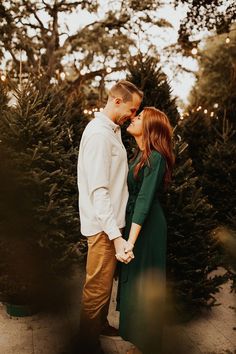 a man and woman standing next to each other in front of christmas trees