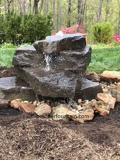 a rock fountain in the middle of a garden