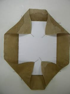 a piece of brown paper is cut in half and placed on top of a white wall