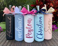 four personalized water bottles with bows on the top one is blue, pink, and white