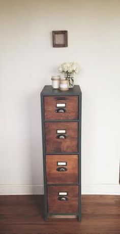 three drawers in a room with white flowers on the top one and a chair next to it