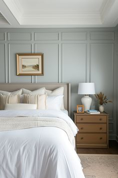 a white bed sitting in a bedroom next to a night stand and dresser with two lamps on top of it