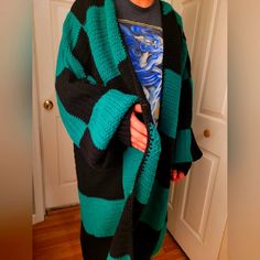 a woman wearing a green and black striped cardigan standing in front of a door