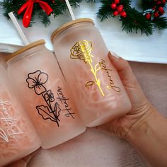 three plastic cups with flowers on them are being held in front of a christmas tree