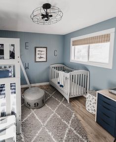 a baby's room with blue walls, white crib and gray rugs