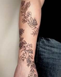 a woman's arm with flowers and leaves on it