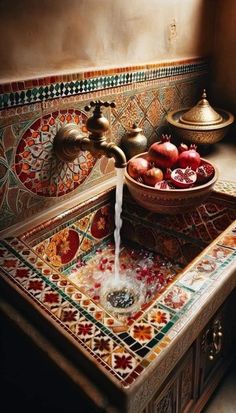 a bowl of pomegranates sits on top of a sink with water running from the faucet