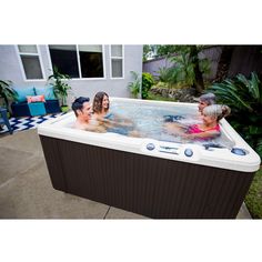 three adults and two children are in an outdoor hot tub with the lid open to look like they're having fun