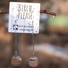 earrings hanging from a branch in front of a sign with birch please written on it