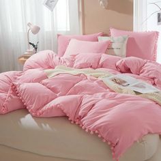 a bed with pink comforters and pillows on it