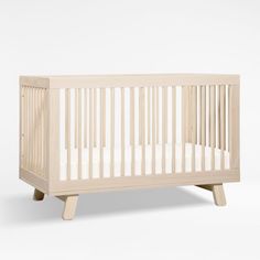 a small wooden crib with white sheets on the bottom and side rails, in front of a white background