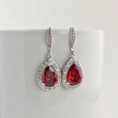 I've created these gorgeous red ruby cubic zirconia bridal tear drop dangle earrings in rhodium plated brass setting. Earrings feature a large teardrop with pear cut red ruby cubic zirconia center surrounded by tiny round zirconia crystals. Teardrop dangles from a cubic zirconia detailed ear wire. Total length of the earring is 3.8 cms. For matching necklace click: https://www.etsy.com/listing/469844682/red-ruby-cubic-zirconia-teardrop-bridal?ref=shop_home_active_26 For matching bracelet click: Elegant Red Drop Crystal Earrings, Red Ruby Drop Earrings, Red Teardrop Dangle Earrings For Formal Occasions, Red Dangle Teardrop Earrings For Formal Occasions, Red Drop Jewelry For Anniversary, Red Ruby Pear-shaped Earrings, Red Dangle Bridal Earrings, Red Drop Bridal Earrings As Gift, Red Dangle Crystal Earrings For Anniversary