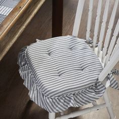 a chair with a cushion on it sitting next to a wooden table and chairs in the background