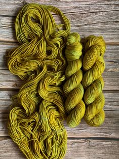 two skeins of yellow yarn sitting on top of a wooden table next to each other