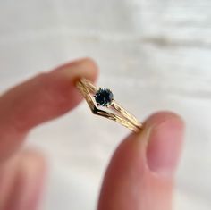 a hand holding a gold ring with a black diamond