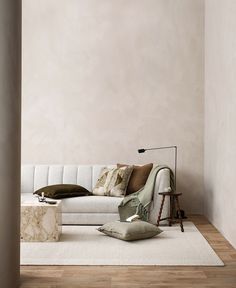 a white couch sitting on top of a wooden floor in a living room next to a lamp