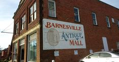 an antique mall sign on the side of a brick building with cars parked in front