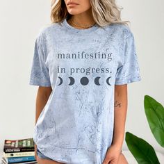 Our Manifest Shirt is the perfect gift for the inspirational person in your life! Featuring a motivational message, a celestial design, and a powerful color blast, this Positive Vibes Shirt will surely be a hit with anyone who wears it. With Manifesting In Progress emblazoned across the front, this shirt is the perfect way to show your love and support! 💫CLOTHING DESCRIPTION Made 100% with incredibly soft, ring-spun cotton, each tee is soft-washed and garment-dyed. Its relaxed fit makes it the Inspirational Crew Neck Shirt With Relaxed Fit, Cotton Moon Print T-shirt In Relaxed Fit, Inspirational Short Sleeve Shirt With Relaxed Fit, Inspirational Short Sleeve Relaxed Fit Shirt, Relaxed Fit Short Sleeve T-shirt With Moon Print, Celestial Shirt, Celestial Design, Men Tie, Motivational Message