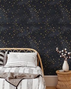 a bed sitting next to a black wall with stars painted on the wall behind it