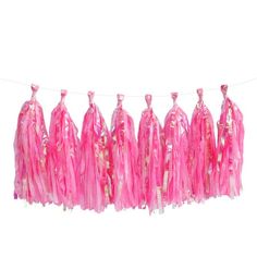 pink and gold tissue tassels hanging on a clothes line against a white background