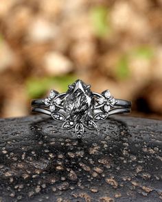 a diamond ring sitting on top of a rock in front of some leaves and rocks