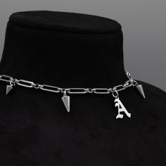 Gothic Style Font Initial Pendant Choker/Necklace, part of our Goth Jewellery Range 15mm x 6mm Solid Stainless Steel Paperclip Chain Gothic Style Stainless Steel Letter Pendant 4 Inch Premium Stainless Steel Adjuster Chain Spiky Gothic Style Choker Necklace Non Tarnish & Waterproof Jewellery Handcrafted in the UK Sizing: Small 11 - 15 Inches (28 - 38cm) Medium 13 - 17 Inches (33 - 43cm) Large 15 - 19 Inches (38 - 48.5cm)