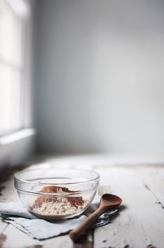 a glass bowl filled with oatmeal sitting on top of a wooden table