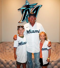 a man and two children posing for a photo in front of a miami marlins sign