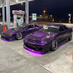 two purple cars parked next to each other at a gas station