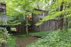 a wooden house in the woods surrounded by trees and bushes with stairs leading up to it