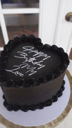 a black heart shaped cake sitting on top of a white table next to a door