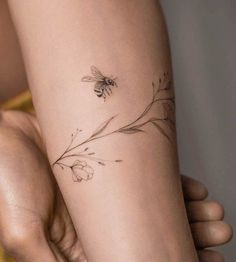 a woman's arm with a flower and bee tattoo on the left side of her arm